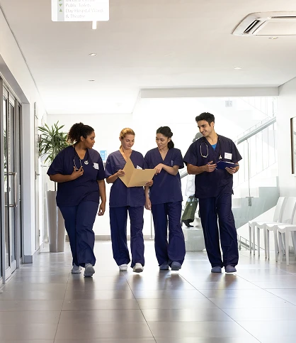 Medical professionals in scrubs walking down a hallway, representing a busy healthcare environment focused on patient care, teamwork, and clinical operations