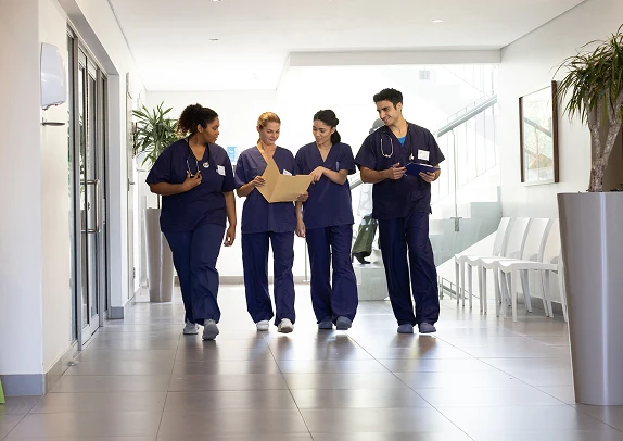 Medical professionals in scrubs walking down a hallway, representing a busy healthcare environment focused on patient care, teamwork, and clinical operations