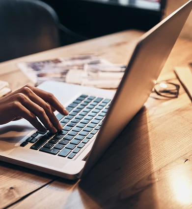 Hand typing on a laptop keyboard, representing digital communication, data entry, or remote work in a professional or academic setting