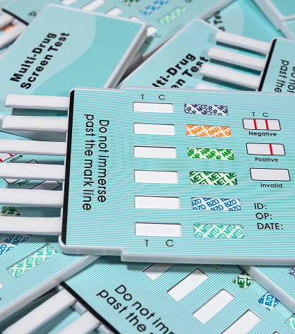 Photo of multiple drug test kits displayed on a surface, showing various test strips and collection containers used for workplace or clinical drug screening